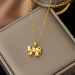 Elegant gold bow pendant necklace with a polished finish on a minimalist cable chain