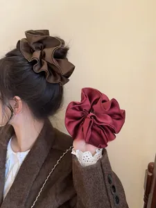 Detail of large satin scrunchies in deep brown and burgundy with elegant silk texture