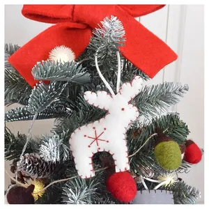 White felt reindeer ornament with red snowflake embroidery on festive Christmas tree