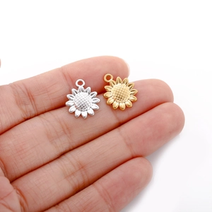 Macro shot of gold and silver stainless steel sunflower pendants on a palm for jewelry DIY