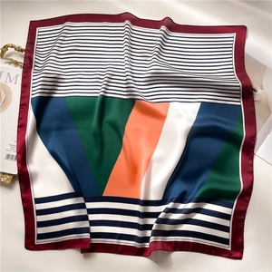Detail view of satin square scarf with geometric stripes and orange-green color blocking