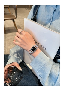 Detail of silver chain link strap and black rectangular dial on a modern women's watch