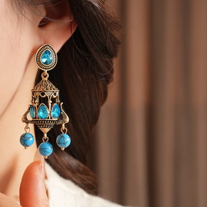 Detailed close-up of vintage bronze chandelier earrings with blue stones on a model