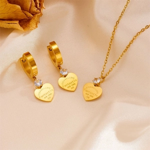 Golden heart jewelry set with zircon on silk background including necklace and earrings