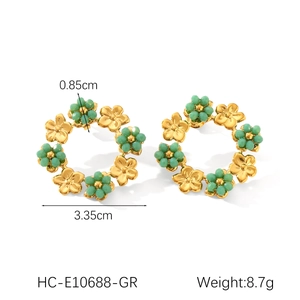 Vue détaillée des boucles d'oreilles fleuries avec pétales d'or et perles vertes