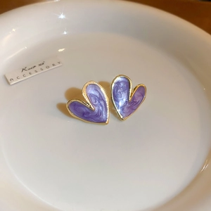 Close-up of vintage gold heart stud earrings with purple marble enamel on a white plate