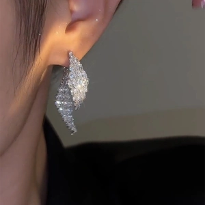 Macro view of crystal leaf earrings showing silver studs and sparkling stone settings