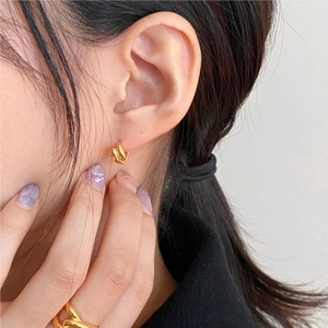 Close-up of gold twist texture hoop earrings and matching ring on elegant model