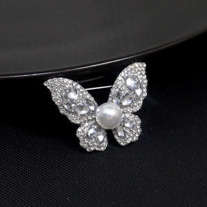 Detailed close-up of a silver butterfly brooch with rhinestones and white pearl inlay