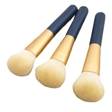 Three eyelash cleansing brushes with cream bristles and blue-gold handles on white background