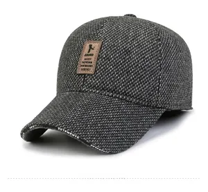 Detail of dark grey wool baseball cap with leather patch and VETEMENTS printed brim