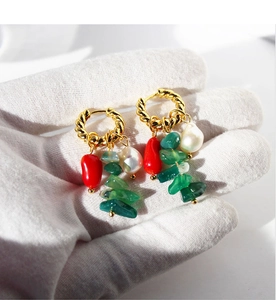 Detail of twisted gold earrings with red drop pendant, natural stones, and white pearl