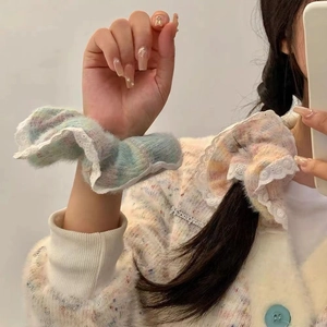Detail of plush rainbow scrunchie with white lace trim worn on wrist and in hair