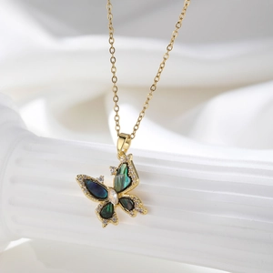 Detail view of a gold butterfly necklace featuring dark green shell inlay and zircon accents