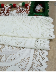 Close-up of white lace table runner with hollow geometric patterns and wavy edges