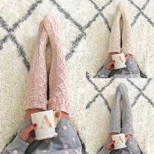 Detail of cable knit wool blend socks in pink beige and grey over soft carpet