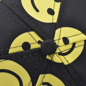 Detailed view of the black baseball cap top button and embroidered yellow smiley face