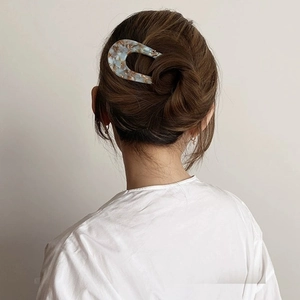 U-shaped hair pin in blue marble with gold foil accents on a minimalist updo