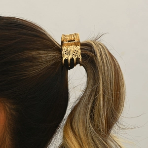 Golden lava texture hair claw clip holding a high ponytail in a side-view professional shot
