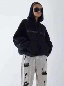Detailed close-up of oversized black hoodie featuring white ETRANGE RULE chest print