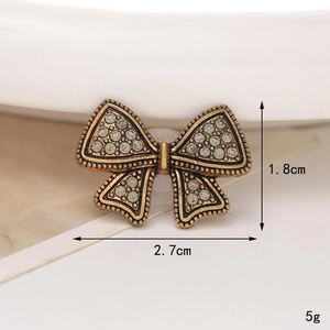 Macro shot of bronze vintage bow shoe charm with rhinestones and size dimensions