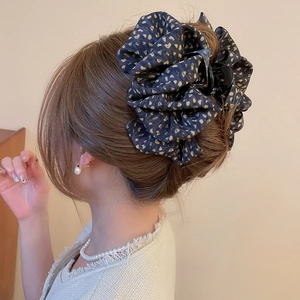 Détail de la grande pince à cheveux en tissu bleu marine à motifs cœurs dorés pour chignon