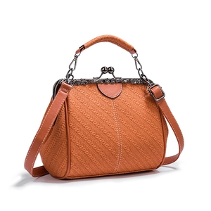 Detail of vintage frame closure on woven PU leather bag with elegant carved metal clasp
