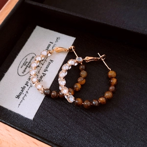 Detailed macro view of 18k gold plated hoop earrings with brown tiger eye and crystal