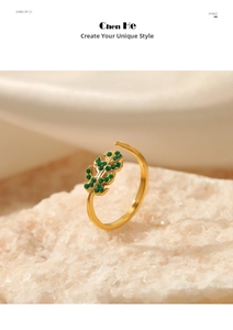 Macro shot of an adjustable leaf-shaped gold ring with green rhinestones on white rock