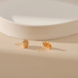 18K gold plated heart stud earrings with sparkling cubic zirconia on beige surface