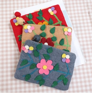 Detail of three handmade wool felt coin purses with floral embroidery in red, brown, and grey