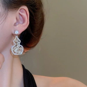 Detailed view of silver hollow gourd earrings with zircon roses on model