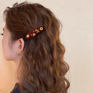 Close-up of red flocked pony hair clip with gold charms worn on curly hair