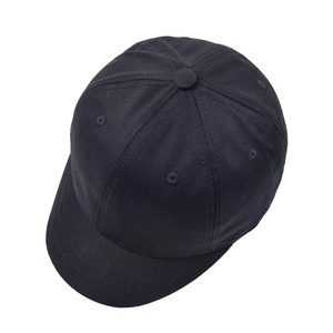 Close-up of black cotton twill baseball cap showing six-panel stitch detail and short brim