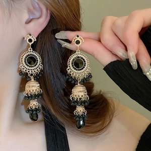Golden vintage Jhumka earrings with black gemstones and beaded tassels on model