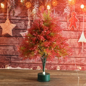 Mini lighted Christmas tree with red-green needles and LED lights on a rustic table