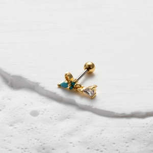 Detail of gold double-headed screw stud earring featuring turquoise and clear stones
