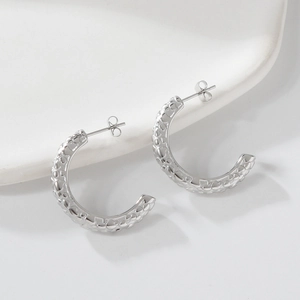 Gros plan sur des boucles d'oreilles en acier argenté en forme de C avec texture martelée