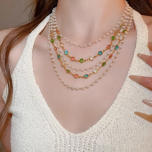 Detailed macro of layered pearl necklace with colorful gemstone accents on gold chain