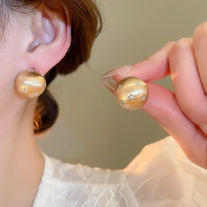 Detail of 18k gold plated matte brushed spherical stud earrings with star-set zircon