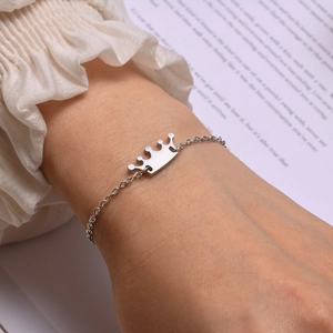 Close-up of a silver crown charm bracelet on a wrist with elegant lifestyle background