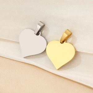 Detail of 18K gold and silver heart pendants on silk fabric showing metal texture