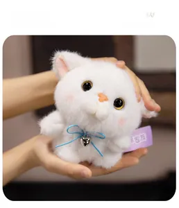 Close-up of white plush kitten toy featuring a blue ribbon and silver heart pendant