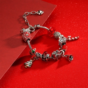 Bracelet à breloques de Noël avec Père Noël, sapin et perles rouges sur fond rouge