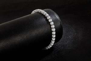 Macro detail of silver tennis bracelet with cubic zirconia stones on a black leather stand