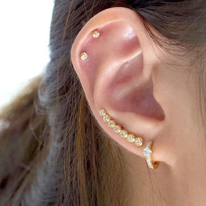 Detailed view of gold cubic zirconia ear crawler and minimalist stud earrings set