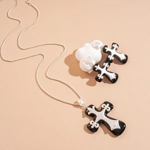 Detail of gothic black resin cross jewelry set with silver filigree patterns on white clouds