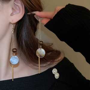 Close-up of long tassel earrings with mother-of-pearl shell texture on a model