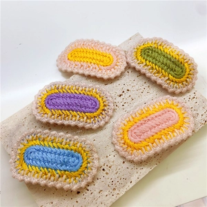 Handmade crochet oval hair clips in five colors on a textured stone surface
