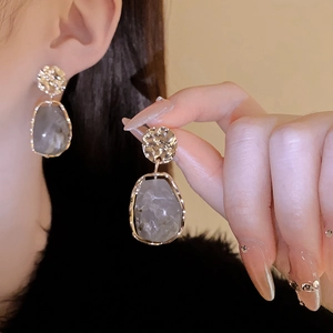Close-up of vintage gold textured metal studs and grey marble resin teardrop earrings